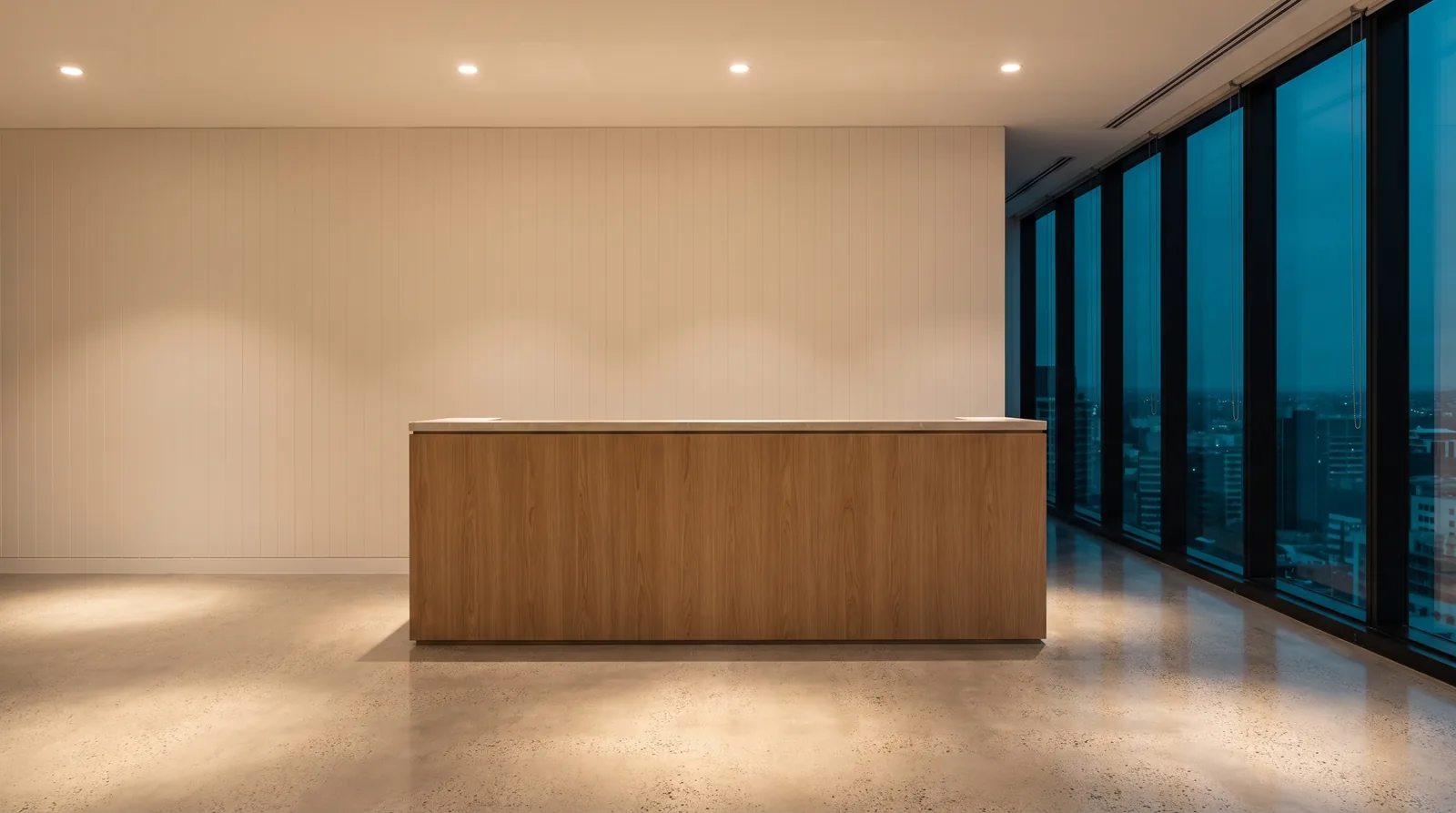 An empty office reception after hours, floors finished and surfaces bare